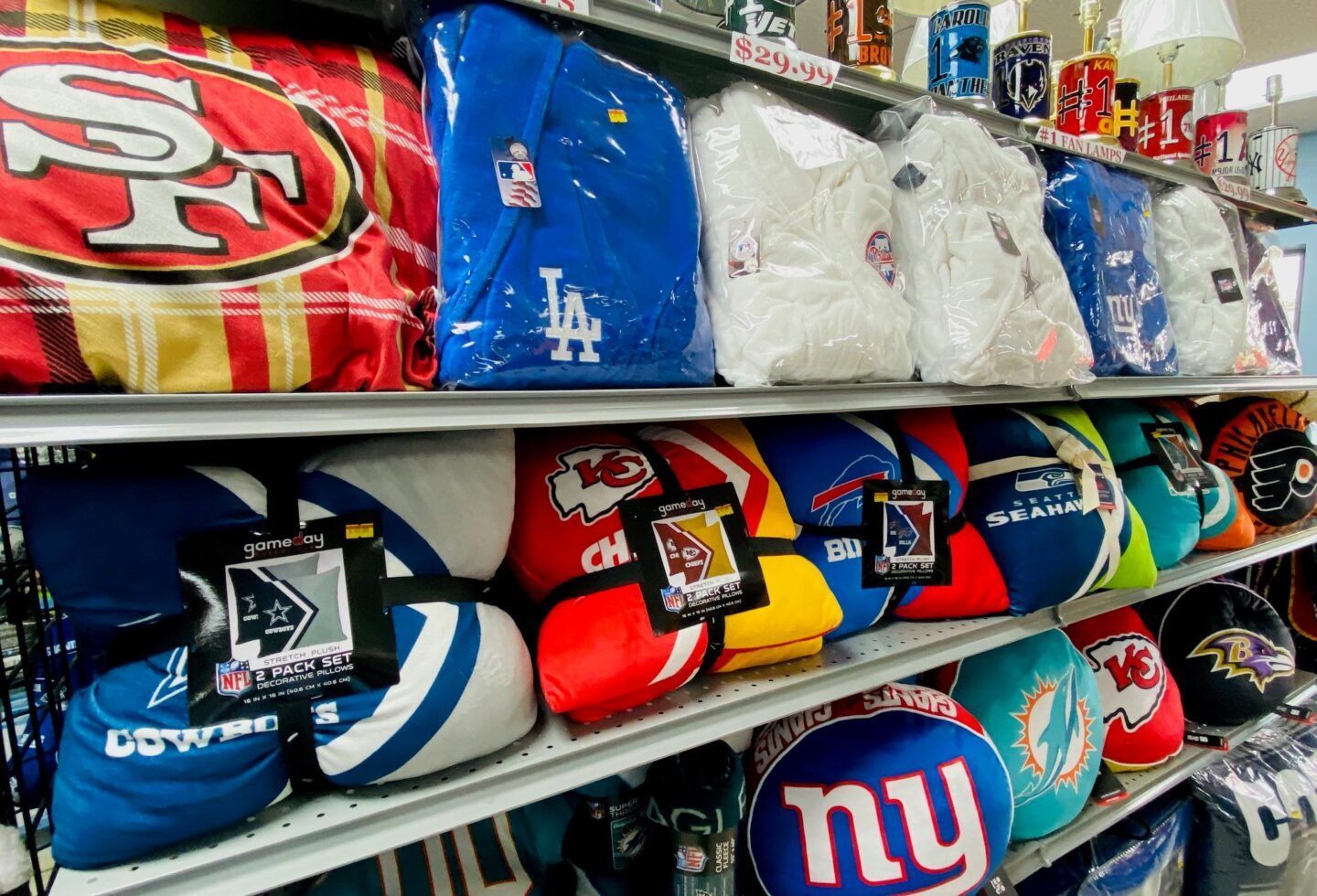 Shelves of colorful NFL team pillows and blankets, including 49ers, Dodgers, and Giants logos