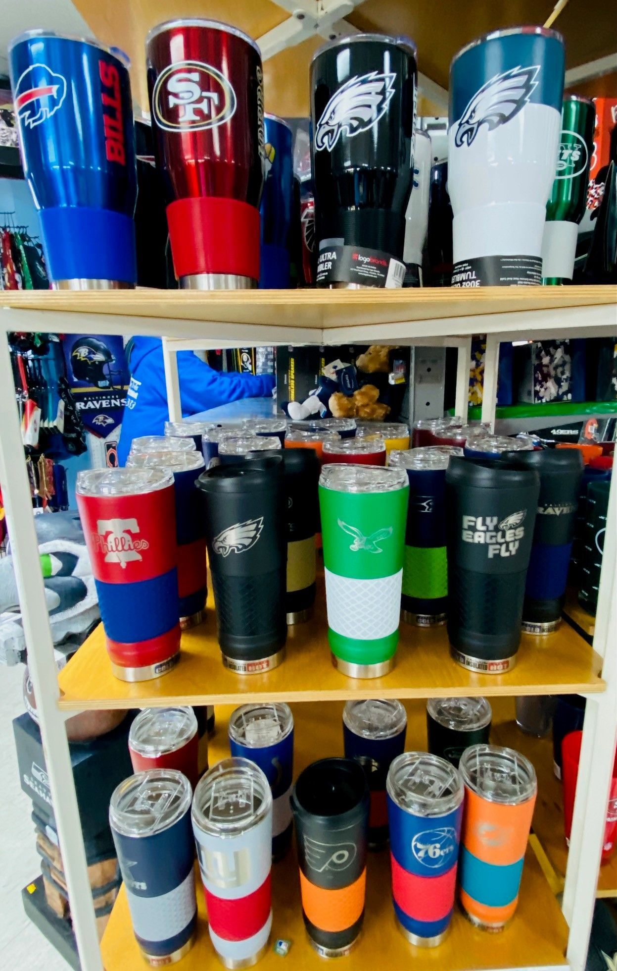 Shelves filled with colorful insulated tumblers and sports team cups in a store display
