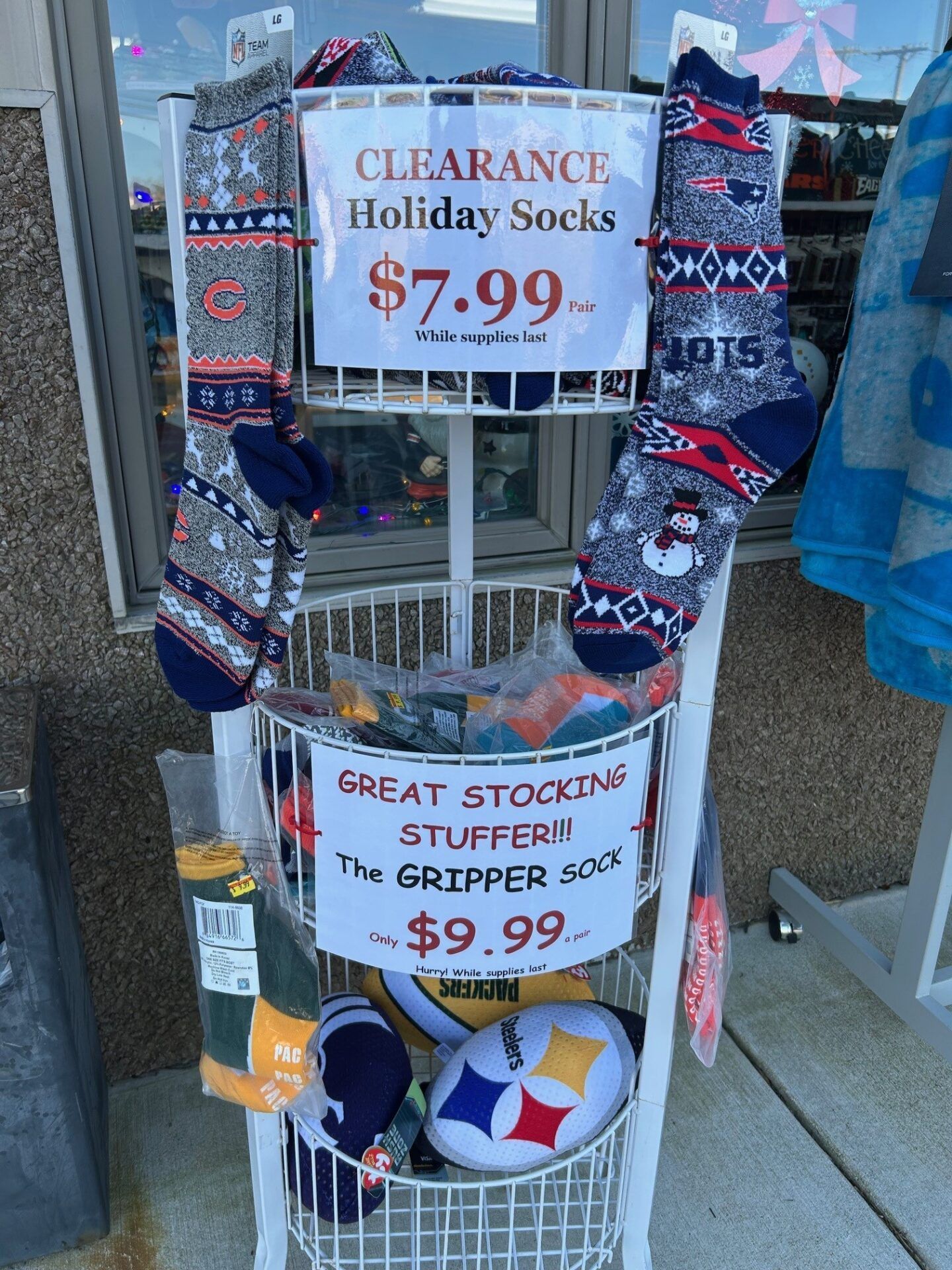 Holiday socks and Grinch toy display with clearance signs at a store entrance.
