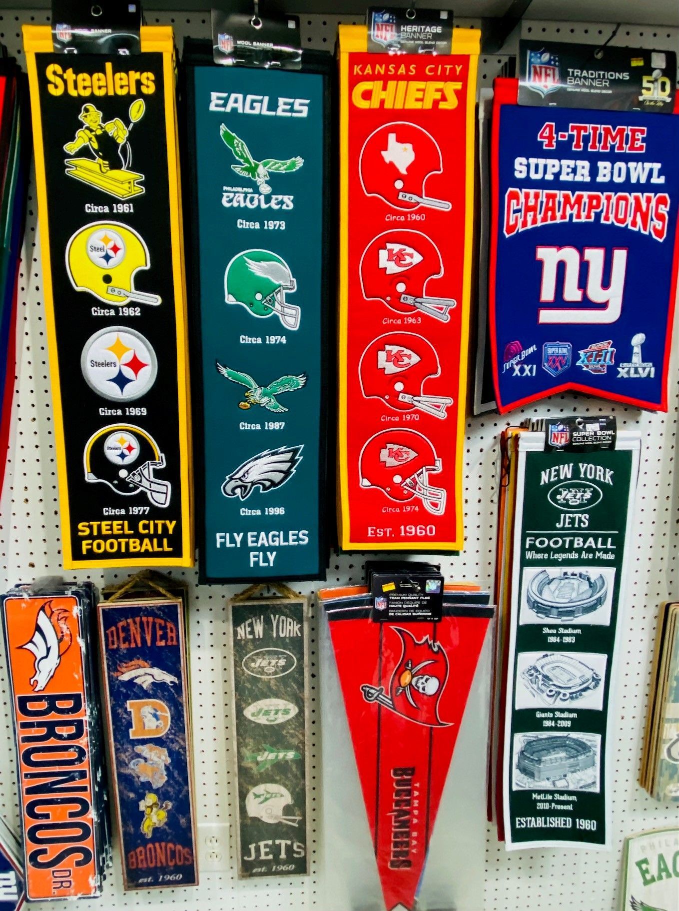 Assorted NFL team pennants hanging on a wall, including Steelers, Eagles, Chiefs, Giants, and Broncos.