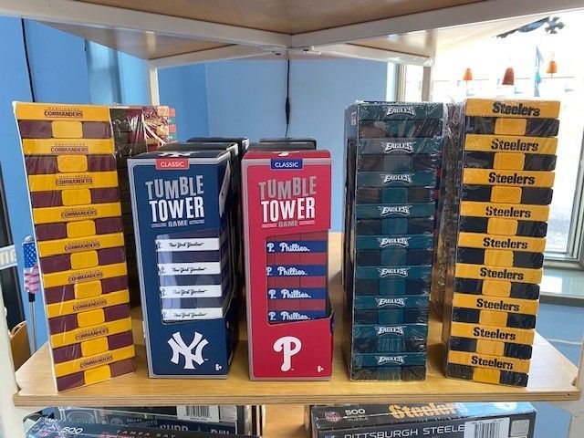 Stacked board game boxes on a shelf, including Tumble Tower and Scattergories, in a store display