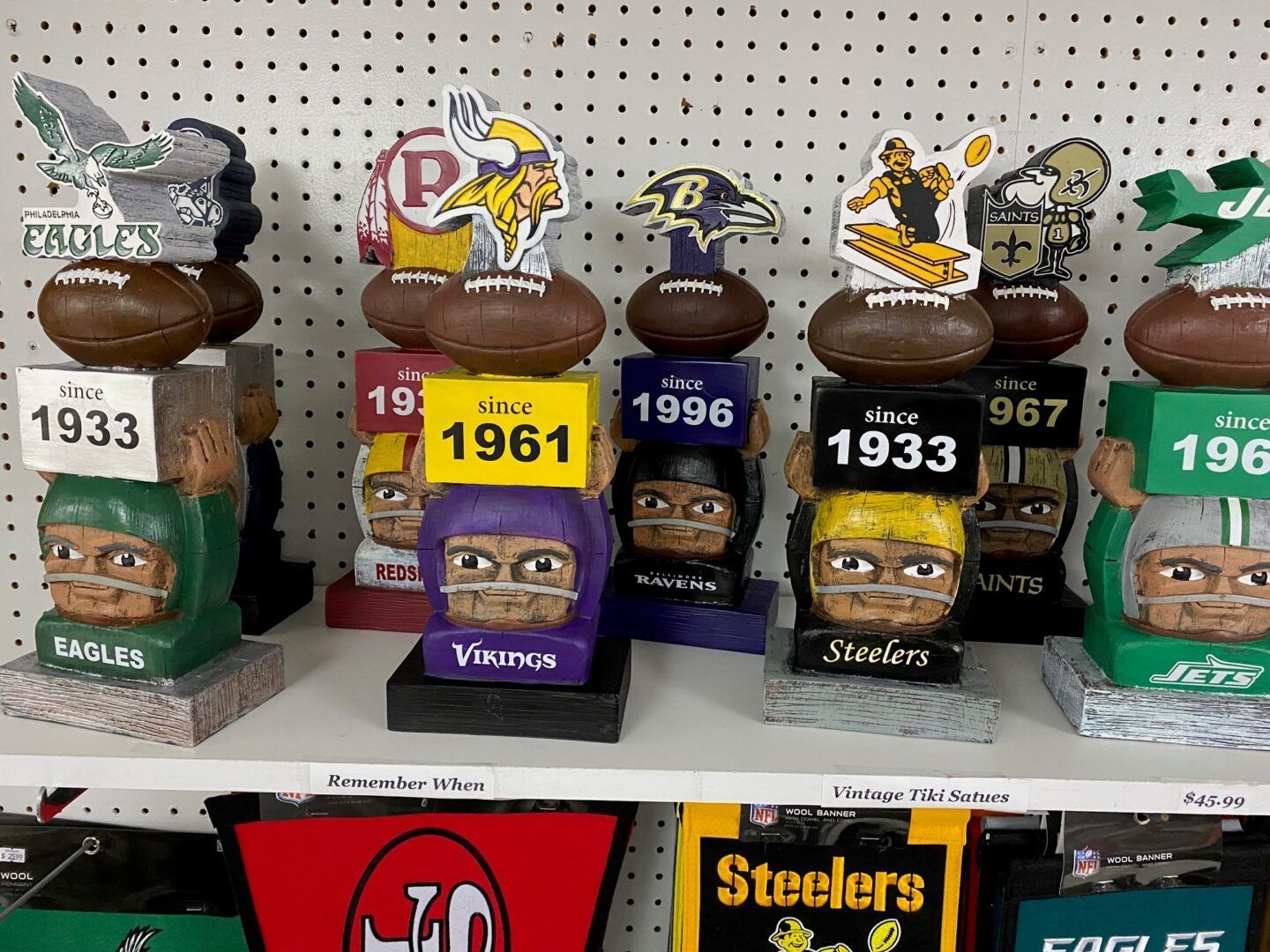 Row of NFL-themed decorative figurines on a store shelf, including Penguins, Vikings, Steelers, and Packers colors.