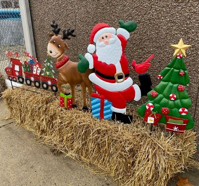 Christmas lawn display with Santa, a reindeer, a decorated tree, and a toy train on hay bales