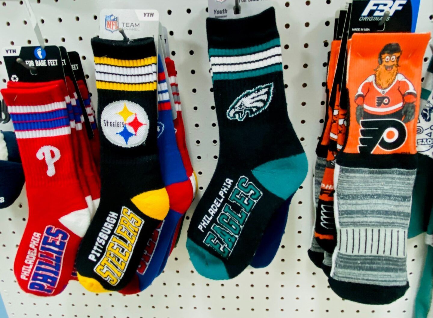 Philadelphia Flyers, Steelers, Eagles, and Flyers-themed sports socks hanging on a pegboard display