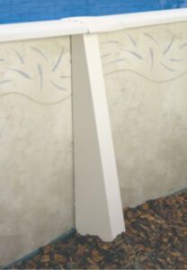 White support column beneath a blue railing against a light patterned wall and gravel ground