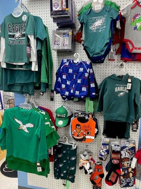 Retail display of green and orange Eagles-themed apparel and accessories on a wall