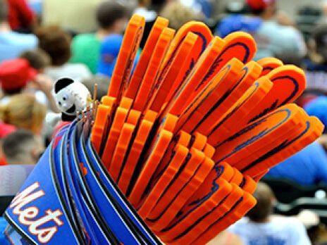 Blue Mets baseball glove with orange laces on a blurred stadium background