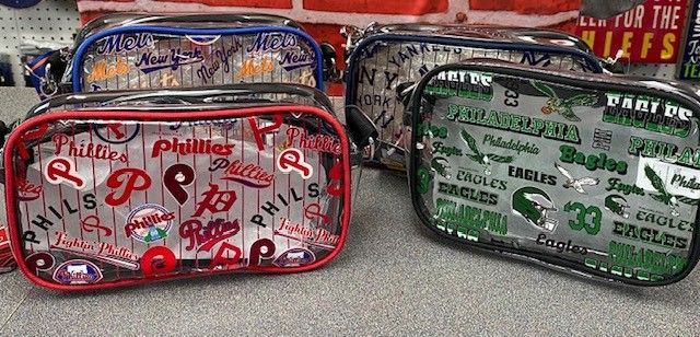 Three patterned zippered pouches in red, blue, and green on a shelf.