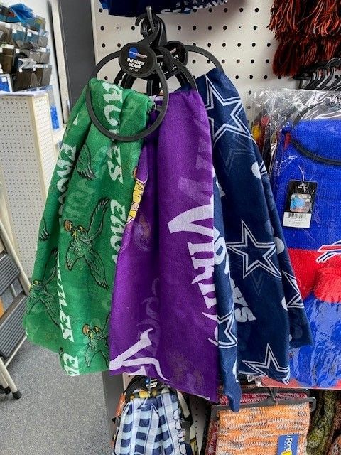 Colorful sports towels hanging on a retail display rack, including green, purple, and blue designs.