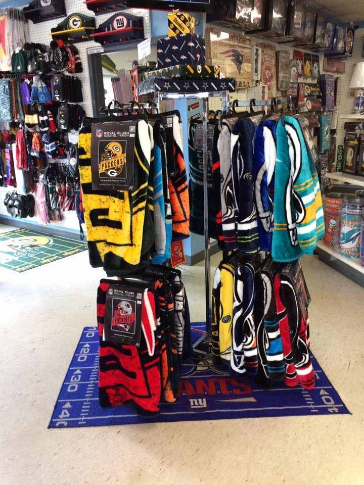 Golf bags displayed in a shop, with colorful bags hanging on racks and standing on a blue mat.