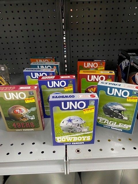 Shelf of UNO card games in blue, red, and green boxes on a store display.