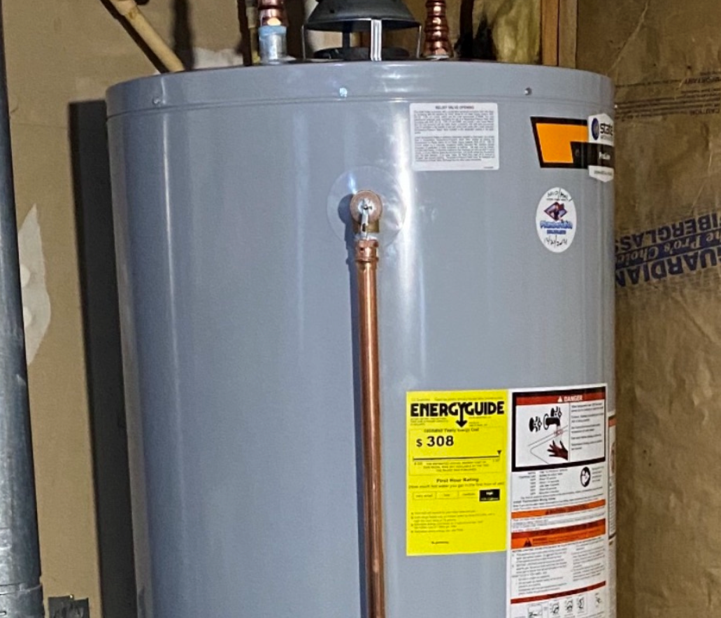 Gray water heater with copper pipes and energy guide sticker in a utility room.