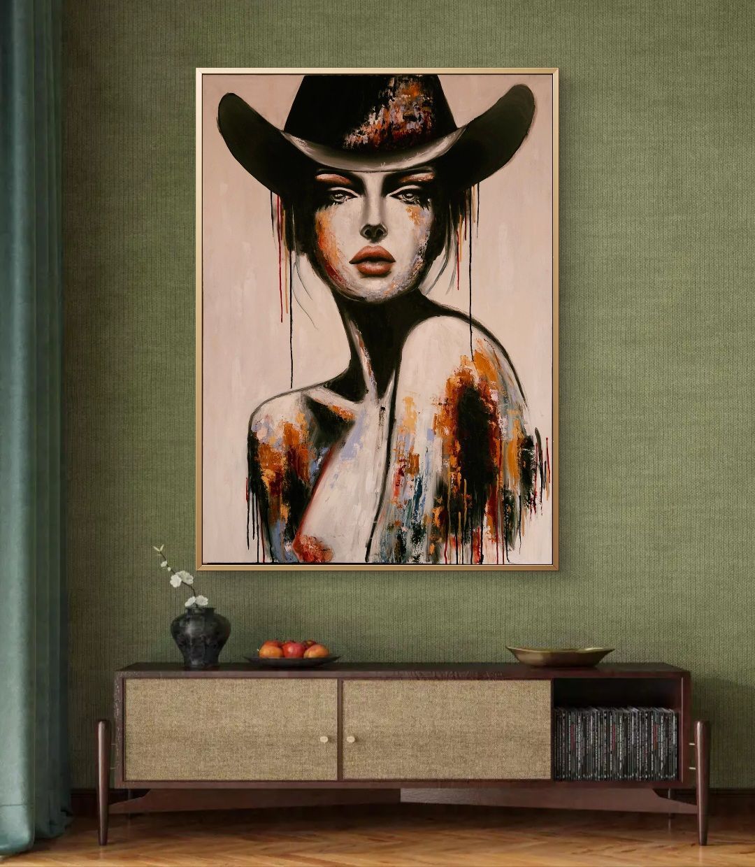 Abstract portret in een ingelijste print boven een laag kastje in een woonkamer met groene muren.