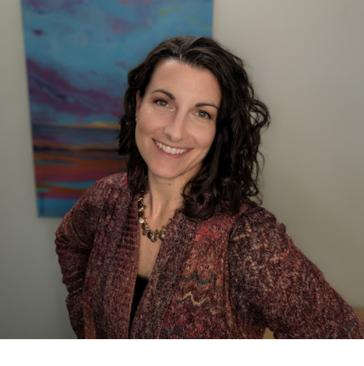 A woman is smiling in front of a painting on the wall.