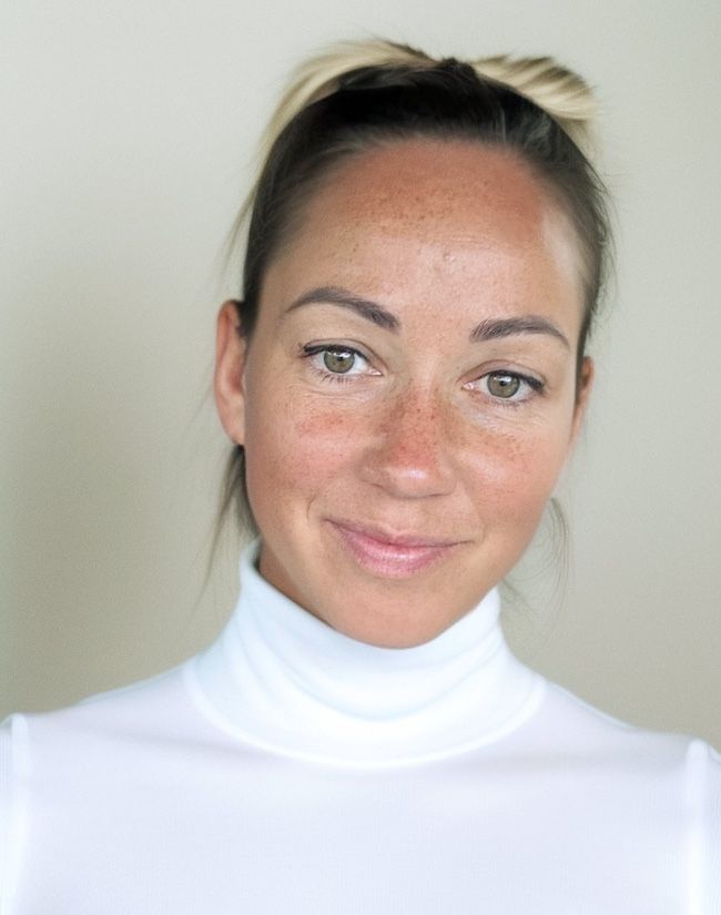 Une femme portant un col roulé blanc sourit à la caméra