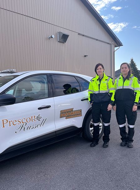 Deux femmes se tiennent à côté d'une voiture devant un bâtiment.