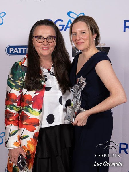 Deux femmes posent pour une photo et l'une tient un trophée