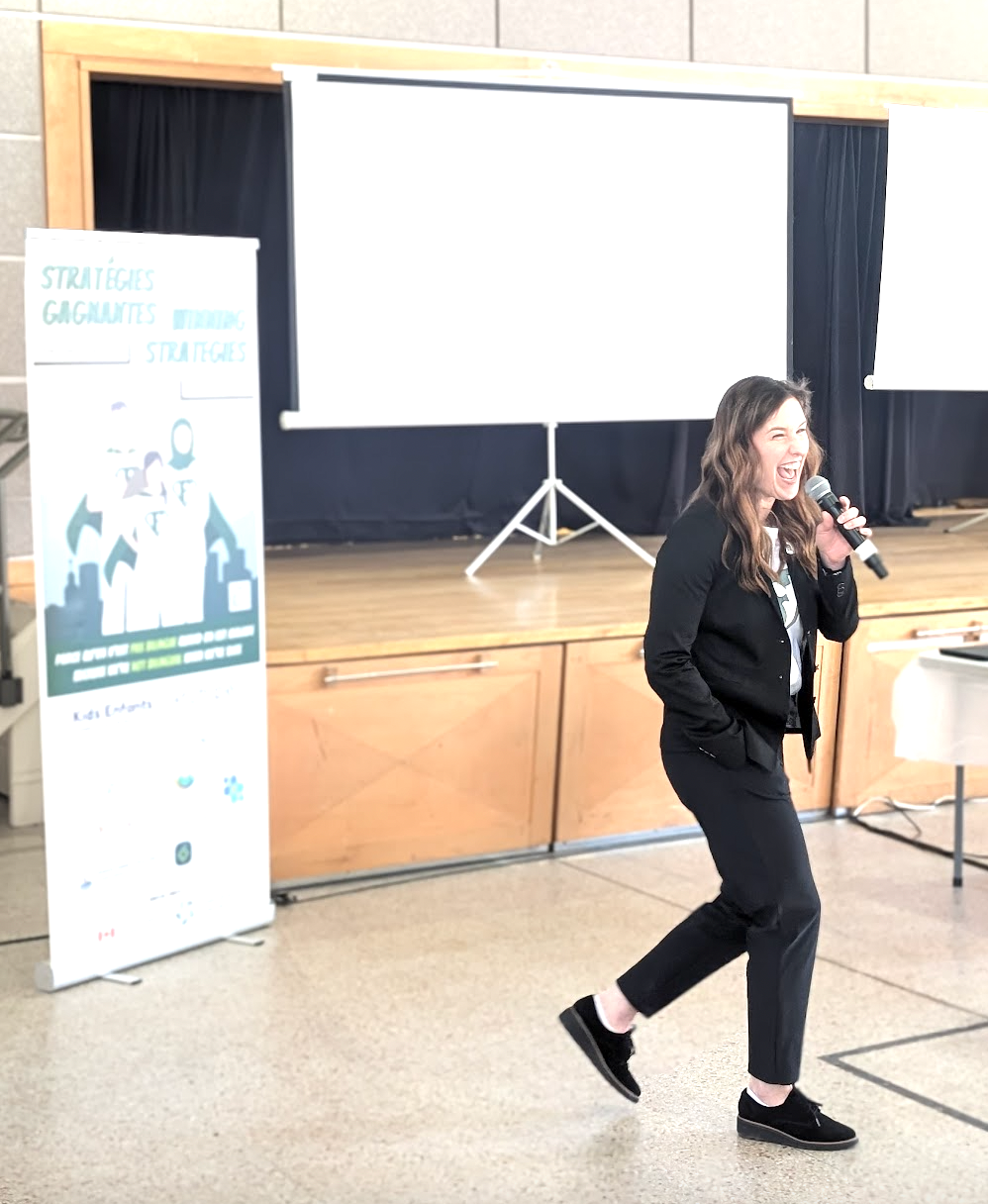 Une femme chante dans un microphone devant un écran de projection