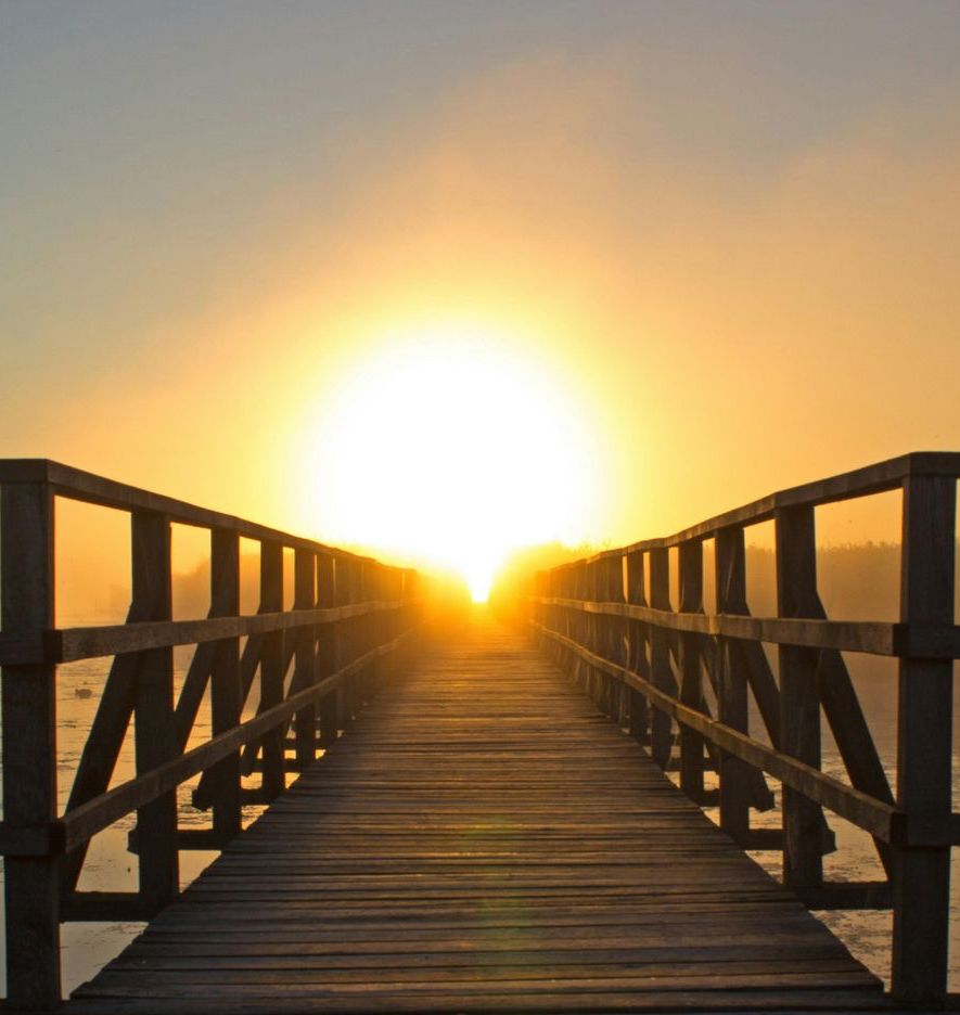Le soleil se couche derrière un pont en bois