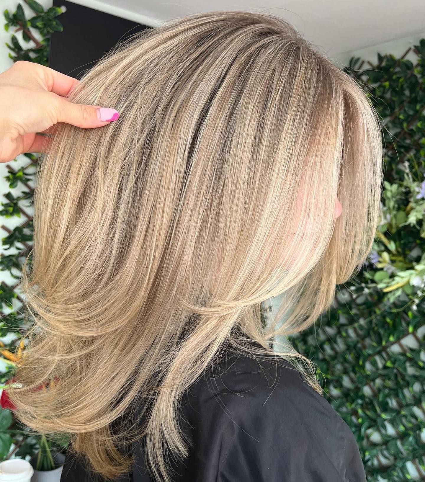 A close-up of long, layered, ash-blonde hair with fine highlights, styled with a crimped texture.