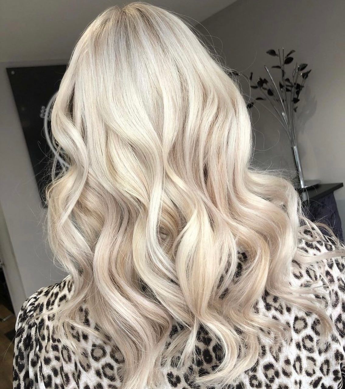 Back view of shoulder-length, wavy platinum blonde hair on a person wearing a leopard print top.