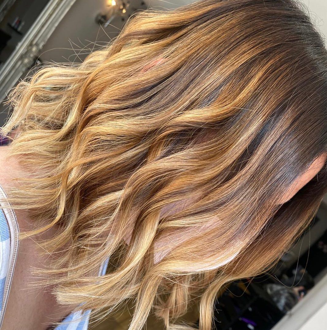 Close-up of hair styled with a crimping iron, featuring warm brown and blonde highlights in distinct, textured waves.