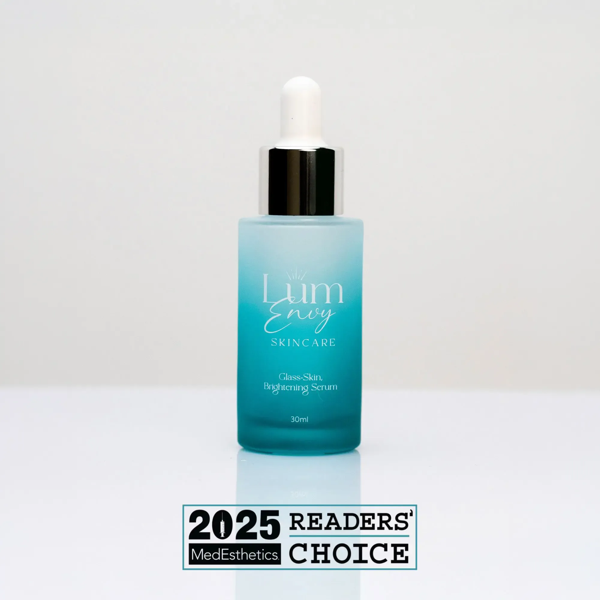 A turquoise glass dropper bottle of LumEnvy serum stands before a 2025 MedEsthetics Readers' Choice award label.