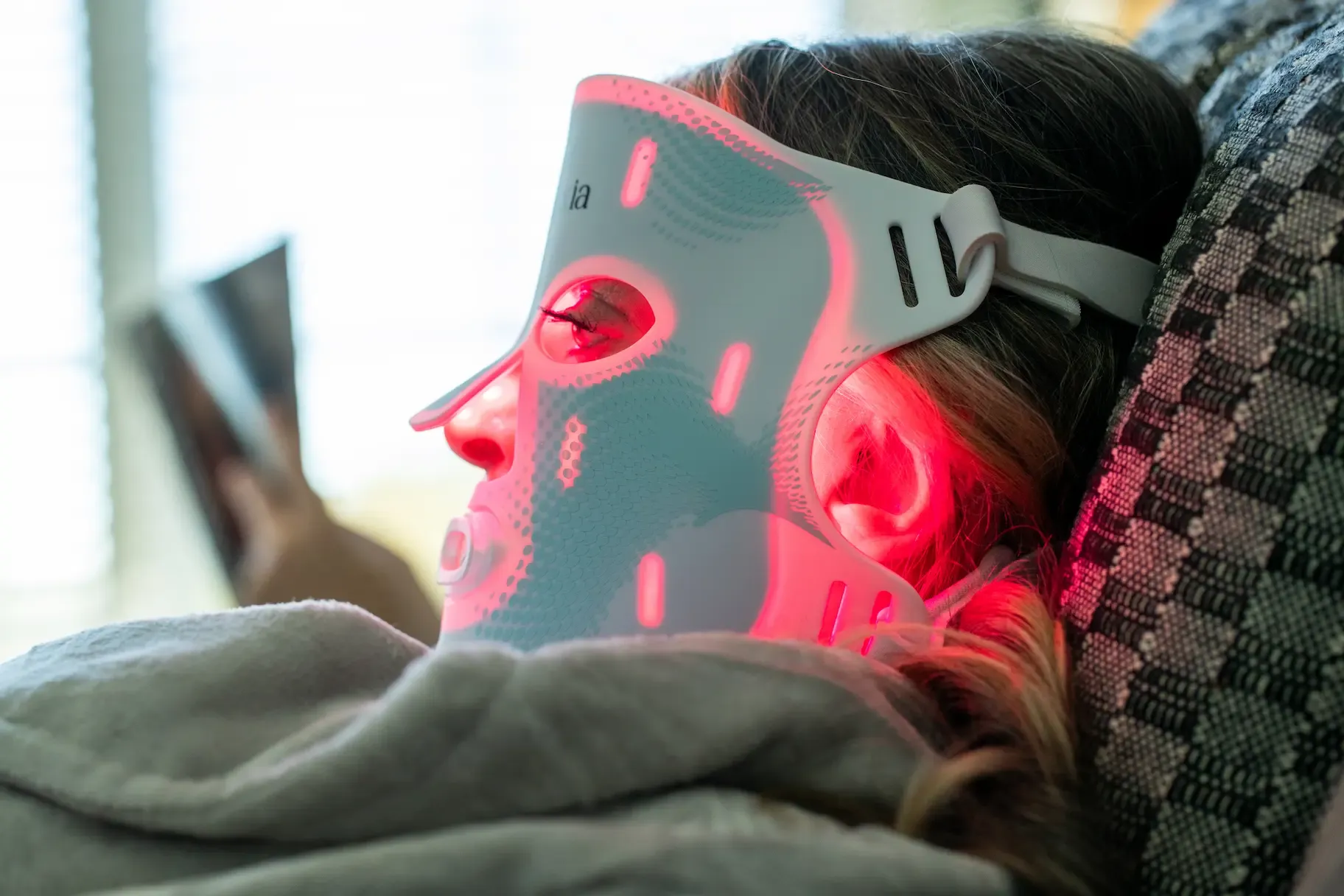 A person using the valluxia infrared face mask in bed