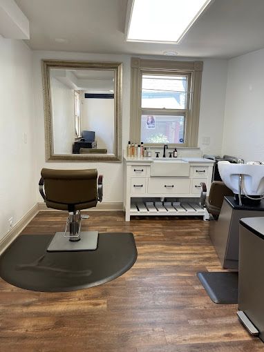 A hair salon with a chair , sink and mirror.