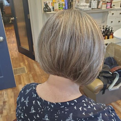 A woman with short blonde hair is sitting in a chair in a salon.