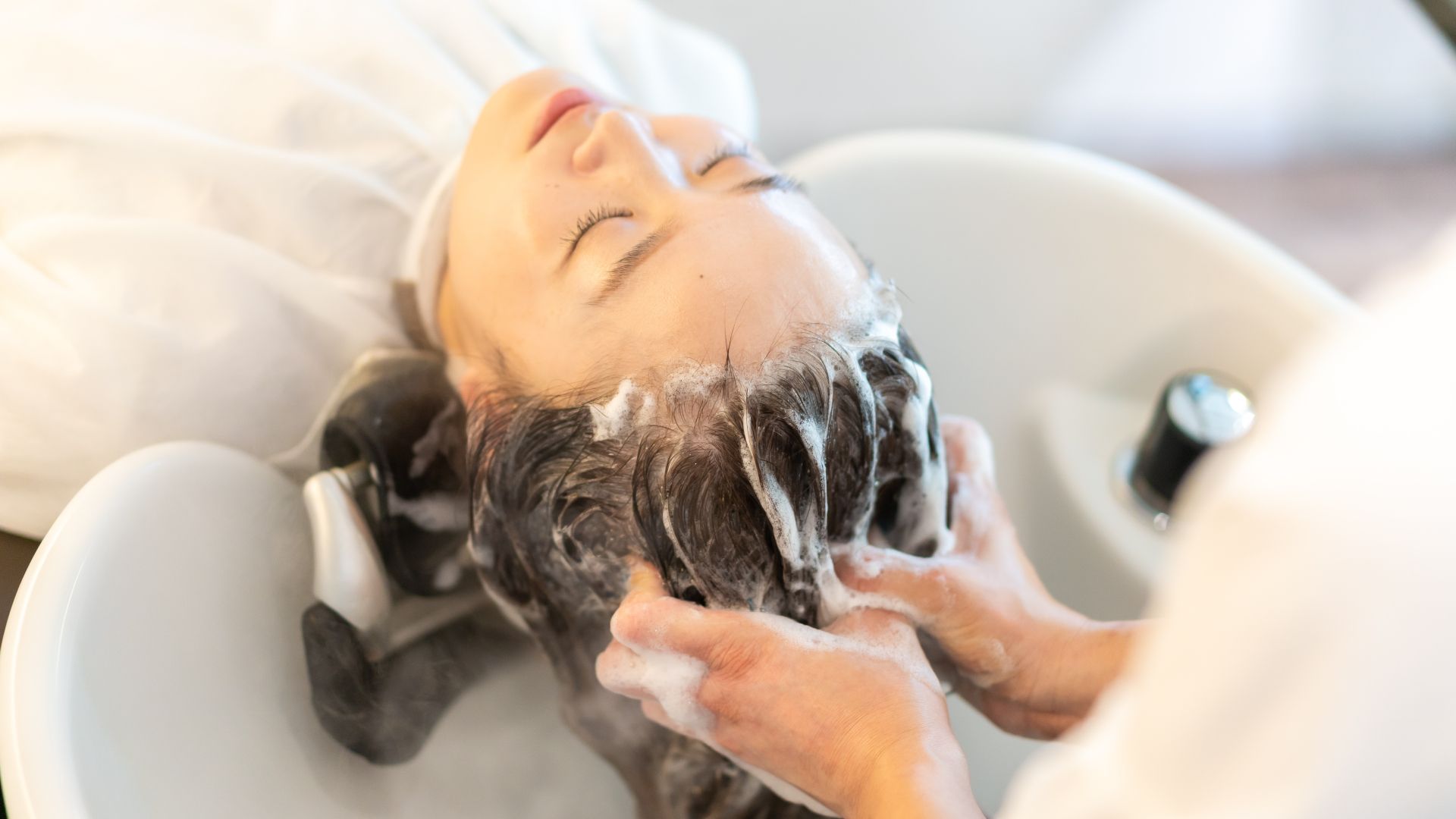 A woman is getting her hair washed in a sink at a salon.