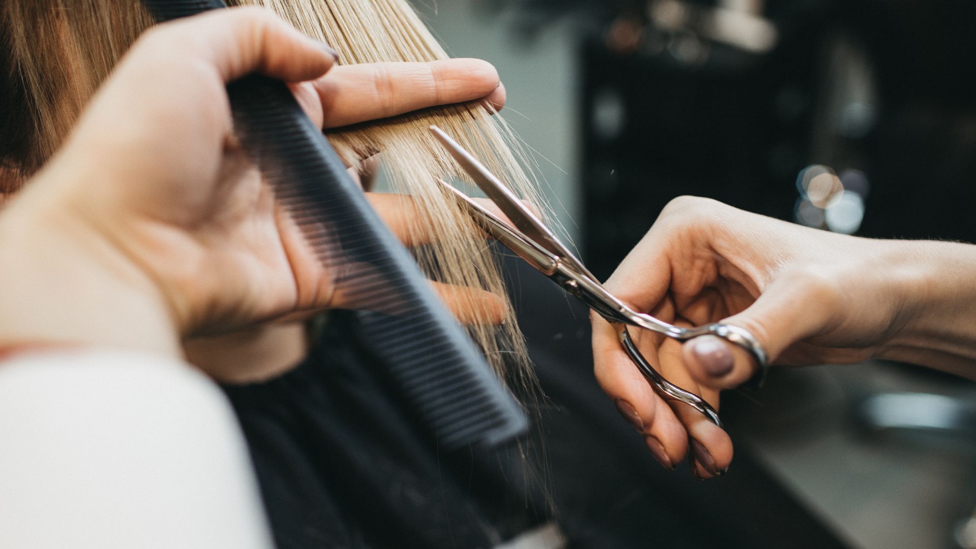 A woman is getting her hair cut by a hairdresser.