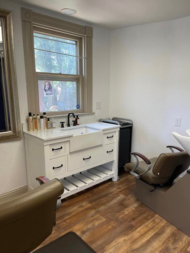 A salon with a sink , chair and mirror.
