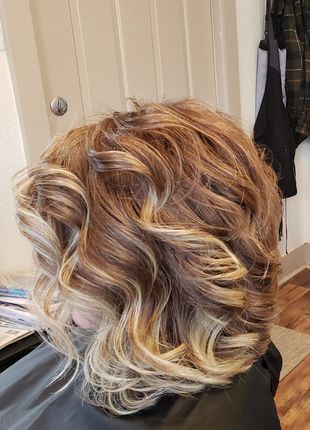 A woman is sitting in a chair with her hair in a bun.