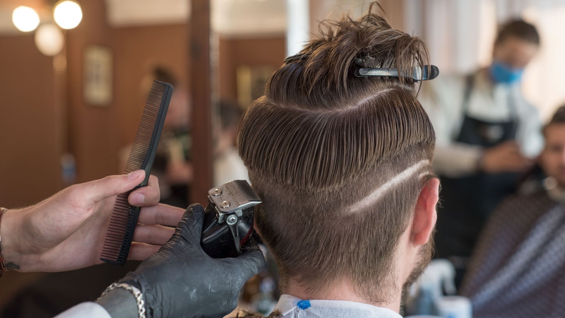 A man is getting his hair cut by a barber in a barber shop.