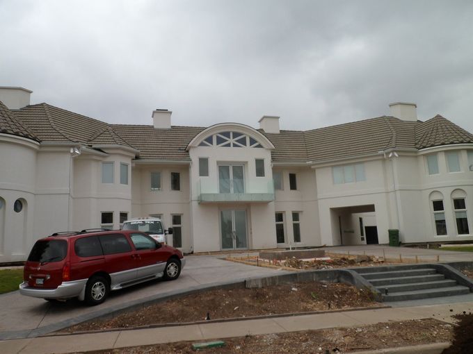 A red van is parked in front of a large white house