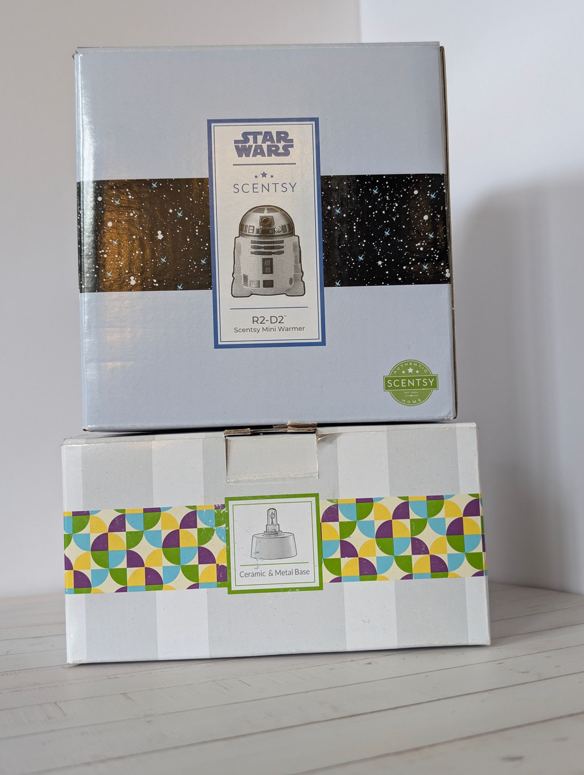 Twee ingepakte dozen, waarvan één met een Star Wars-thema, op elkaar gestapeld op een witte ondergrond. R2-D2 Disney