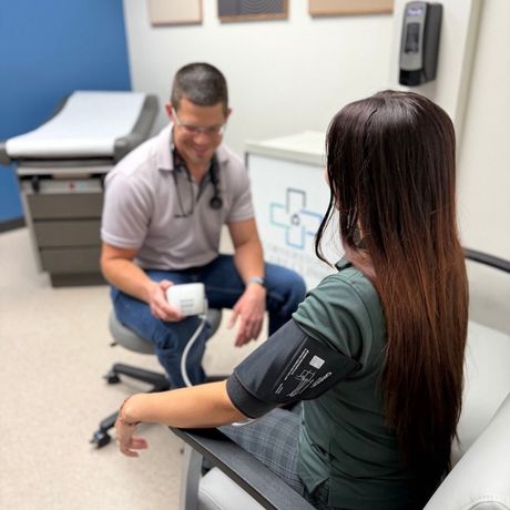 Doctor taking a patient’s blood pressure in a clinic exam room