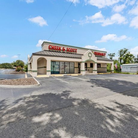 Healthcare storefront with red sign, parking lot, and blue sky