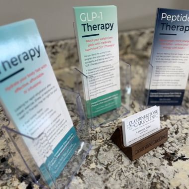 Clinic countertop with brochure stands for GLP-1 therapy and peptide therapy, plus a small business card holder.