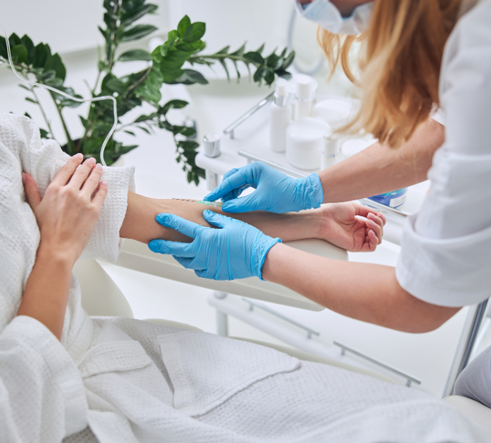 Healthcare worker in blue gloves applying an IV in a bright clinic room