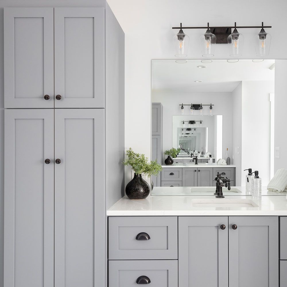 A bathroom with gray cabinets , a sink , and a large mirror.
