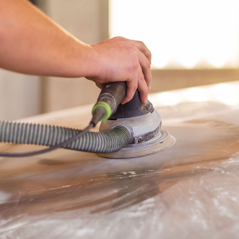 A person is sanding a piece of wood with a sander.