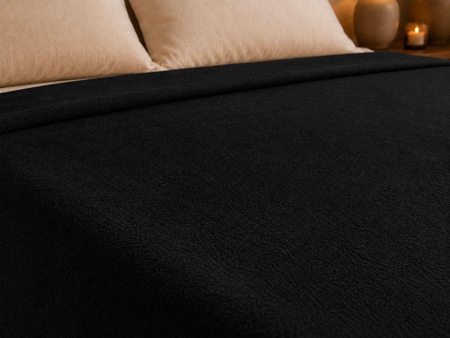 Habitación acogedora con una cama vestida con ropa de cama negra, almohadas blancas y luz natural cálida.