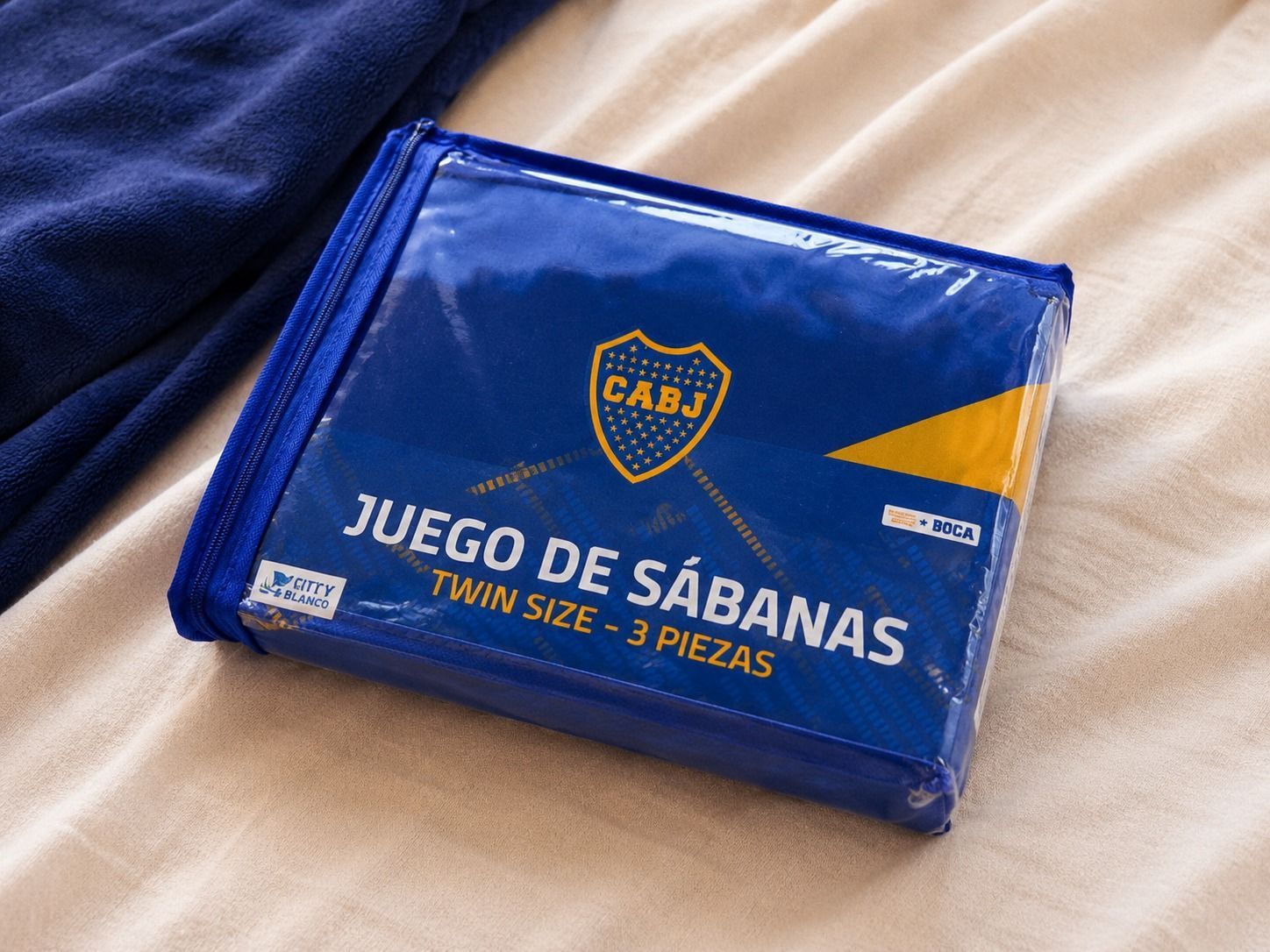 Colcha azul y amarilla de Boca Juniors sobre una cama en una habitación luminosa.