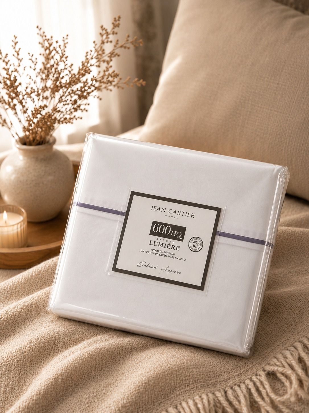 Almohadas y ropa de cama blancas sobre una cama de madera junto a una mesita de noche con un jarrón con plantas.