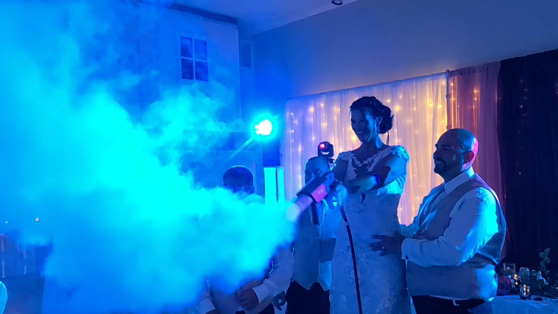 A bride and groom are standing in front of a microphone with smoke coming out of it.