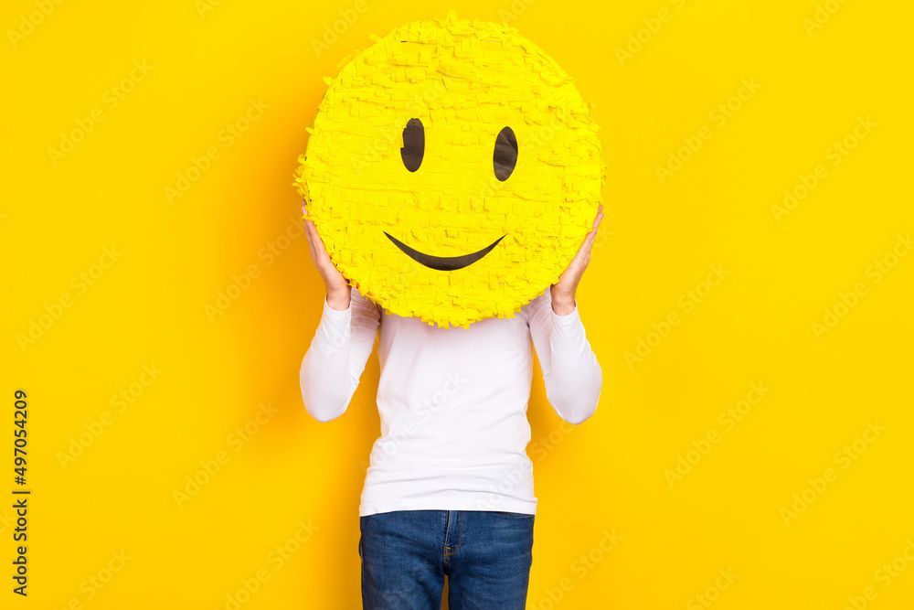 Person holding a large yellow smiley face in front of their head against a yellow background.