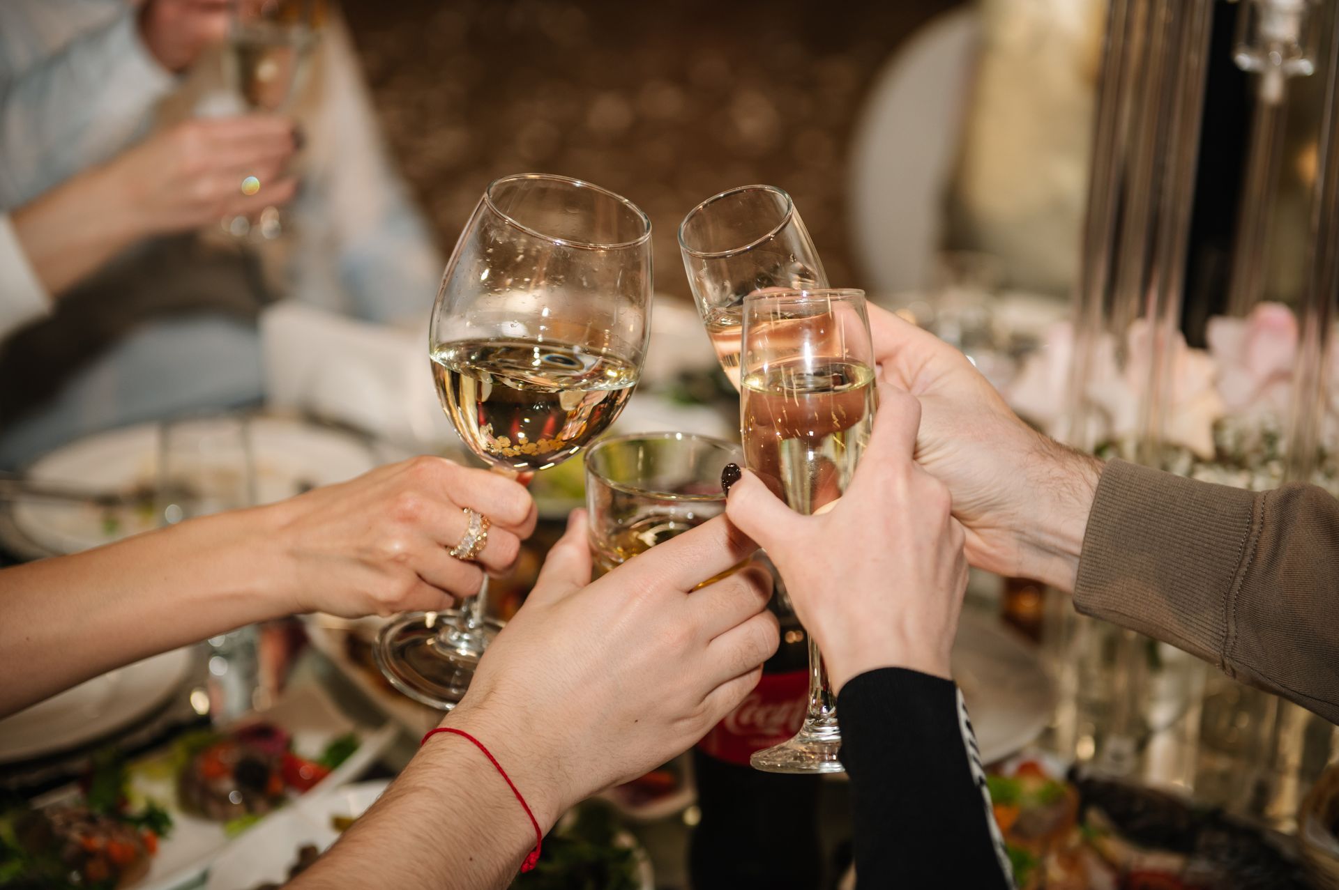 Hands raising champagne glasses at a festive dinner table with candles and flowers Hands raising champagne glasses at a festive dinner table with candles and flowers