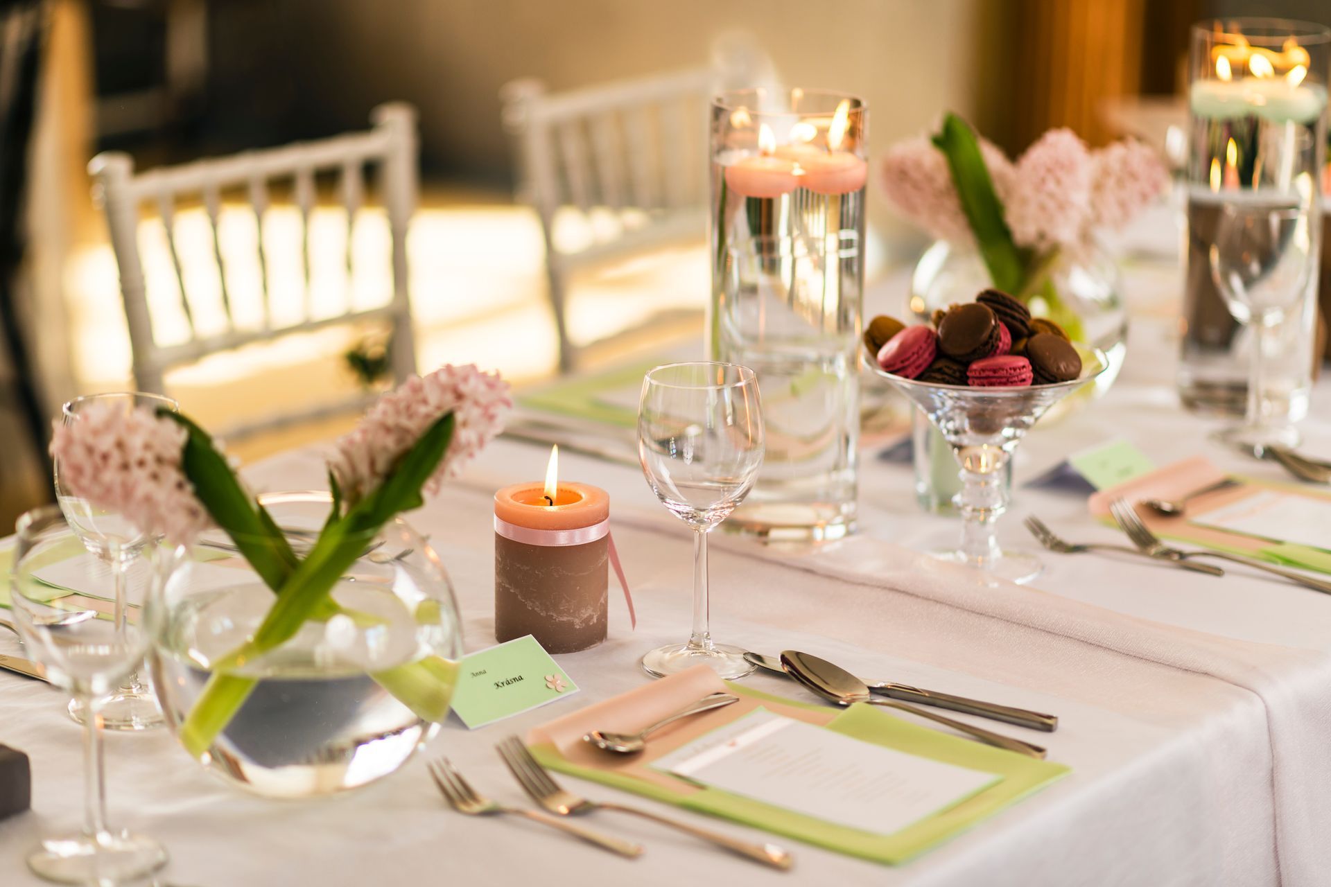 Elegant outdoor dining table set with flowers, candles, glasses, and place settings in warm sunlight Elegant outdoor dining table set with flowers, candles, glasses, and place settings in warm sunlight